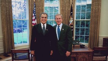 Movie still from “Fahrenheit 9/11” (2004), directed by Michael Moore – A couple of men standing next to each other in a room; Medium shot, Low angle