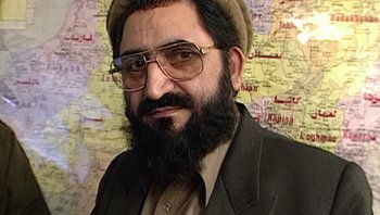Movie still from “Fahrenheit 9/11” (2004), directed by Michael Moore – A man with a beard wearing glasses and wearing a hat; Close Up shot, High angle