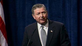Movie still from “Fahrenheit 9/11” (2004), directed by Michael Moore – A person wearing a suit and tie; Close Up shot, High angle