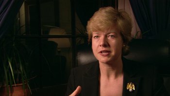 Movie still from “Fahrenheit 9/11” (2004), directed by Michael Moore – A person wearing a suit and tie; Close Up shot, Over the shoulder angle