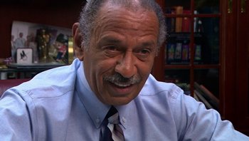 Movie still from “Fahrenheit 9/11” (2004), directed by Michael Moore – An older man wearing a blue dress shirt and a tie; Close Up shot, High angle