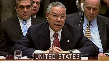 Movie still from “Fahrenheit 9/11” (2004), directed by Michael Moore – A person sitting at a table in front of a microphone; Close Up shot, Low angle