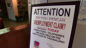 Movie still from “Fahrenheit 9/11” (2004), directed by Michael Moore – An unemployment claim sign is posted in front of a building; Wide shot, High angle