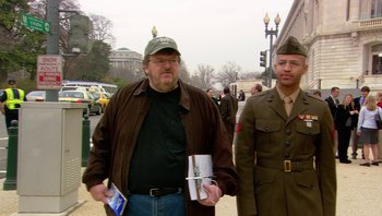 Movie still from “Fahrenheit 9/11” (2004), directed by Michael Moore – A man in a brown jacket and a man in a green hat; Medium shot, Over the shoulder angle
