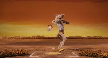 Movie still from “Fantastic Mr. Fox” (2009), directed by Wes Anderson – A cat wearing shorts and a t - shirt swinging at a ball; Wide shot, Over the shoulder angle