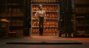 Movie still from “Fantastic Mr. Fox” (2009), directed by Wes Anderson – A man standing in front of shelves filled with bottles; Wide shot, Low angle