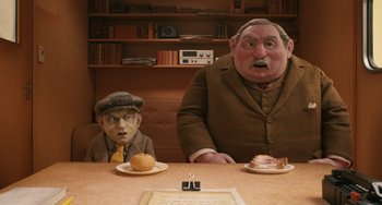 Movie still from “Fantastic Mr. Fox” (2009), directed by Wes Anderson – A man sitting at a dinner table with a fake head; Medium shot, High angle