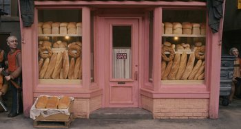 Movie still from “Fantastic Mr. Fox” (2009), directed by Wes Anderson – A store front that has bread on the outside of the store; Wide shot, High angle