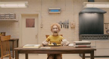 Movie still from “Fantastic Mr. Fox” (2009), directed by Wes Anderson – A man sitting at a table with a plate of food; Medium shot, High angle