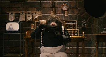 Movie still from “Fantastic Mr. Fox” (2009), directed by Wes Anderson – A person with a stuffed animal on their head and holding a phone; Medium shot, High angle