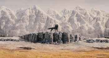 Movie still from “Fantastic Mr. Fox” (2009), directed by Wes Anderson – A black wolf standing on top of a pile of rocks; Extreme Wide shot, Low angle
