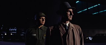 Movie still from “Fantastic Voyage” (1966), directed by Richard Fleischer – A man in a hat and a man in a suit and tie; Medium shot, Low angle