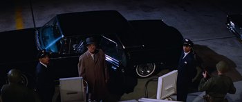 A man standing next to a car in a dark room