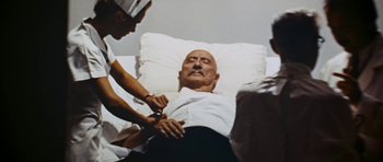 Movie still from “Fantastic Voyage” (1966), directed by Richard Fleischer – A man in a hospital bed being assisted by two nurses; Medium shot, High angle