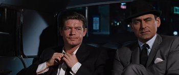 Movie still from “Fantastic Voyage” (1966), directed by Richard Fleischer – A person sitting in a car wearing a suit; Medium shot, Over the shoulder angle