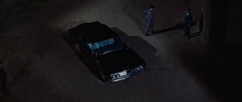Movie still from “Fantastic Voyage” (1966), directed by Richard Fleischer – A man walking next to an old car at night; Extreme Wide shot, High angle