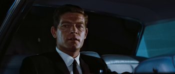 Movie still from “Fantastic Voyage” (1966), directed by Richard Fleischer – A man wearing a suit and tie sitting in the back of a car; Close Up shot, Low angle