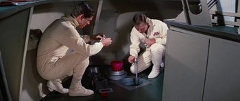 Movie still from “Fantastic Voyage” (1966), directed by Richard Fleischer – Two men in white suits are working in a room; Medium shot, High angle