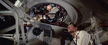 Movie still from “Fantastic Voyage” (1966), directed by Richard Fleischer – Two men are looking into a mirror in a room; Medium shot, Overhead angle