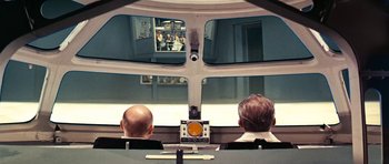 Movie still from “Fantastic Voyage” (1966), directed by Richard Fleischer – Two men are sitting in the back of an airplane looking out the window; Wide shot, Over the shoulder angle