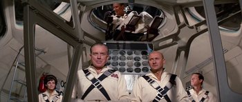 Movie still from “Fantastic Voyage” (1966), directed by Richard Fleischer – Two men sitting in a space station with a helmet on; Medium shot, Low angle
