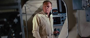 Movie still from “Fantastic Voyage” (1966), directed by Richard Fleischer – An older man in a tan suit is holding a radio; Medium shot, Low angle