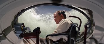 Movie still from “Fantastic Voyage” (1966), directed by Richard Fleischer – A man sitting in a chair in front of the ocean; Medium shot, High angle