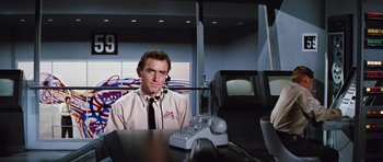 Movie still from “Fantastic Voyage” (1966), directed by Richard Fleischer – A man sitting in front of a tv in a room; Medium shot, Low angle