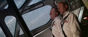 Movie still from “Fantastic Voyage” (1966), directed by Richard Fleischer – Two men are looking out the window of an airplane; Medium shot, Low angle