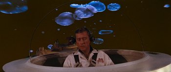 Movie still from “Fantastic Voyage” (1966), directed by Richard Fleischer – A man sitting in front of a projection of jellyfish; Medium shot, High angle