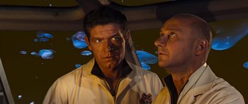 Movie still from “Fantastic Voyage” (1966), directed by Richard Fleischer – Two men standing next to each other in front of a wall; Medium shot, Over the shoulder angle