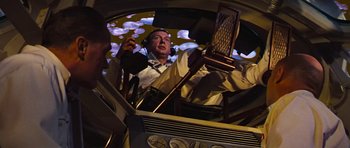 Movie still from “Fantastic Voyage” (1966), directed by Richard Fleischer – A man is sitting in a car with headphones on; Medium shot, Low angle