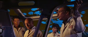Movie still from “Fantastic Voyage” (1966), directed by Richard Fleischer – A group of people standing next to each other in a car; Medium shot, Low angle