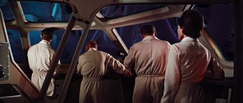 Movie still from “Fantastic Voyage” (1966), directed by Richard Fleischer – A man and a woman holding hands while standing on a plane; Medium shot, Low angle