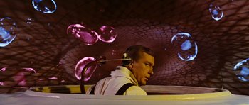 Movie still from “Fantastic Voyage” (1966), directed by Richard Fleischer – A man in a white jacket is sitting in a car; Medium shot, Low angle