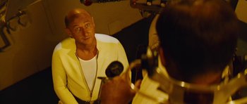 A bald man in a white shirt is in front of a mirror