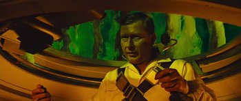Movie still from “Fantastic Voyage” (1966), directed by Richard Fleischer – A man holding a violin while sitting in a car; Medium shot, Low angle
