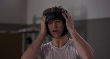 Movie still from “Fat City” (1972), directed by John Huston – A young man wearing a boxing helmet in a gym; Close Up shot, Low angle