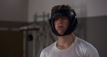 Movie still from “Fat City” (1972), directed by John Huston – A young man wearing a boxing helmet in a gym; Close Up shot, Over the shoulder angle