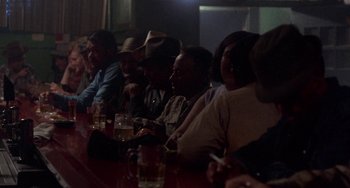 Movie still from “Fat City” (1972), directed by John Huston – A group of people sitting at a table with drinks in front of them; Wide shot, Over the shoulder angle