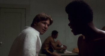 Movie still from “Fat City” (1972), directed by John Huston – A group of young men sitting in a room talking; Medium shot, Over the shoulder angle