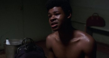 Movie still from “Fat City” (1972), directed by John Huston – A young black man sitting in a dark room; Close Up shot, High angle