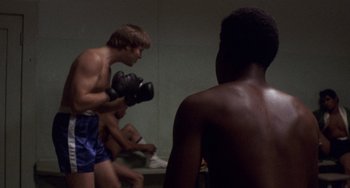 Movie still from “Fat City” (1972), directed by John Huston – A group of young men standing next to each other in a room; Medium shot, Over the shoulder angle