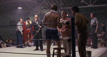 Movie still from “Fat City” (1972), directed by John Huston – A group of men standing in a boxing ring; Wide shot, Over the shoulder angle
