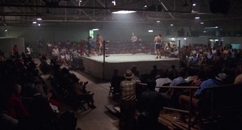 Movie still from “Fat City” (1972), directed by John Huston – A crowd of people watching a wrestling match in an indoor arena; Extreme Wide shot, High angle