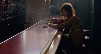Movie still from “Fat City” (1972), directed by John Huston – A woman sitting at a table with a glass of beer; Medium shot, High angle