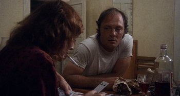 Movie still from “Fat City” (1972), directed by John Huston – A man and a woman sitting at a table playing cards; Medium shot, Over the shoulder angle