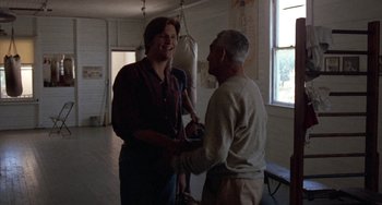 Movie still from “Fat City” (1972), directed by John Huston – A man and a woman shaking hands in a room; Medium shot, Over the shoulder angle