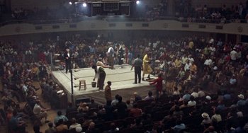 Movie still from “Fat City” (1972), directed by John Huston – A boxing match in an arena with a crowd watching it; Extreme Wide shot, High angle