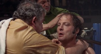 Movie still from “Fat City” (1972), directed by John Huston – A man is being shaved by two other men; Close Up shot, Over the shoulder angle